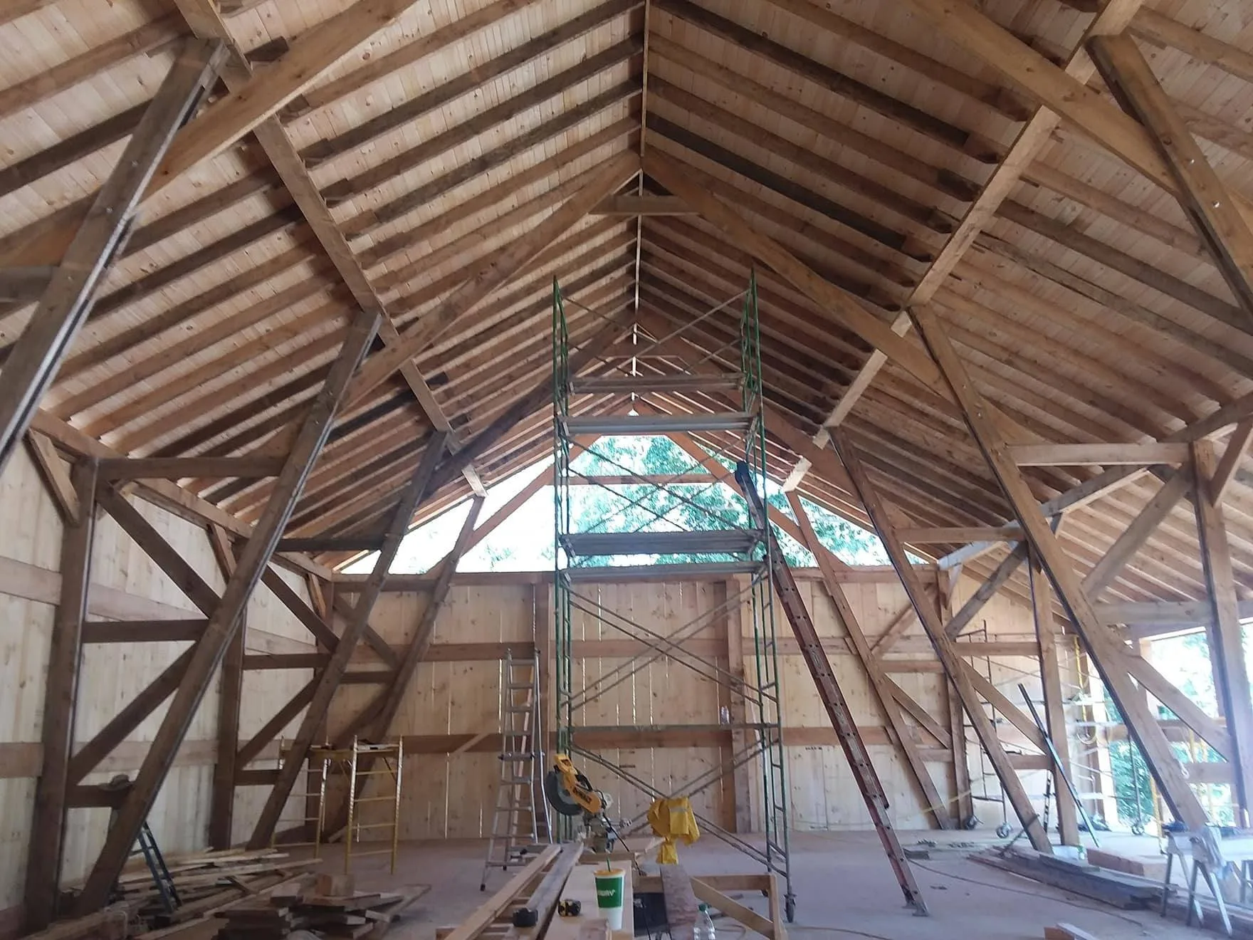 An unfinished interior of a wooden structure with exposed beams and a scaffold in the center.
